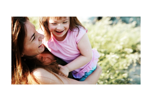 Child using no tech communication- smiling with parent figure. 